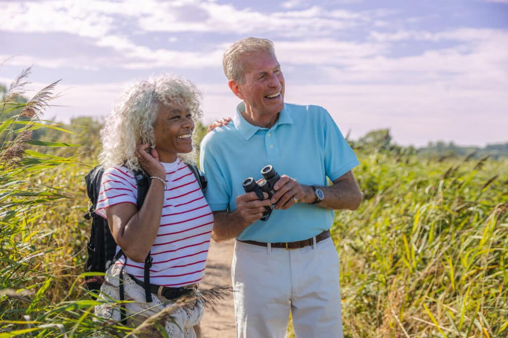Couple exploring the surroundings with binoculars, enjoying nature and scenic views.