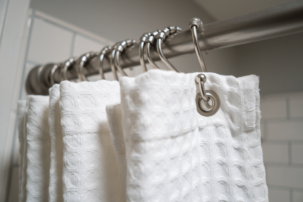 White shower curtain in a compact bathroom setup to decorate your static caravan with a clean, fresh look.