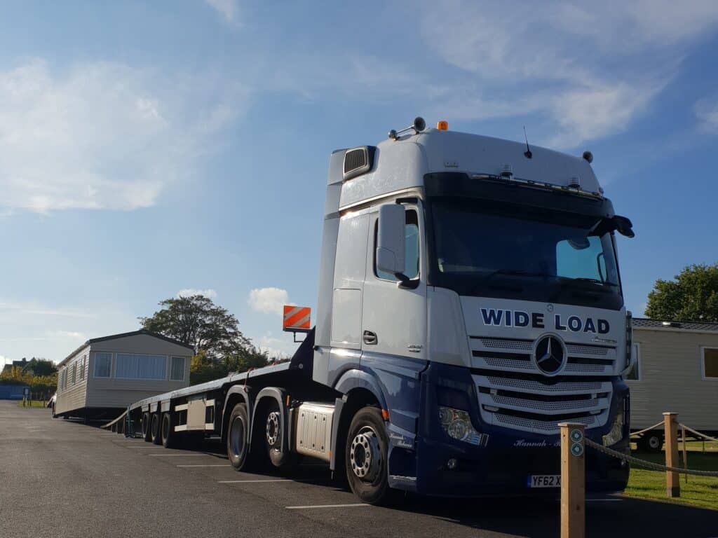 Lorry loading a static caravan onto its trailer, showing the transportation process at a caravan park.