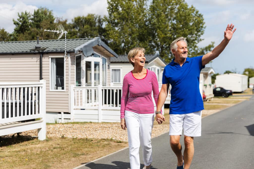 Happy couple waving to friendly community at a welcoming holiday site.