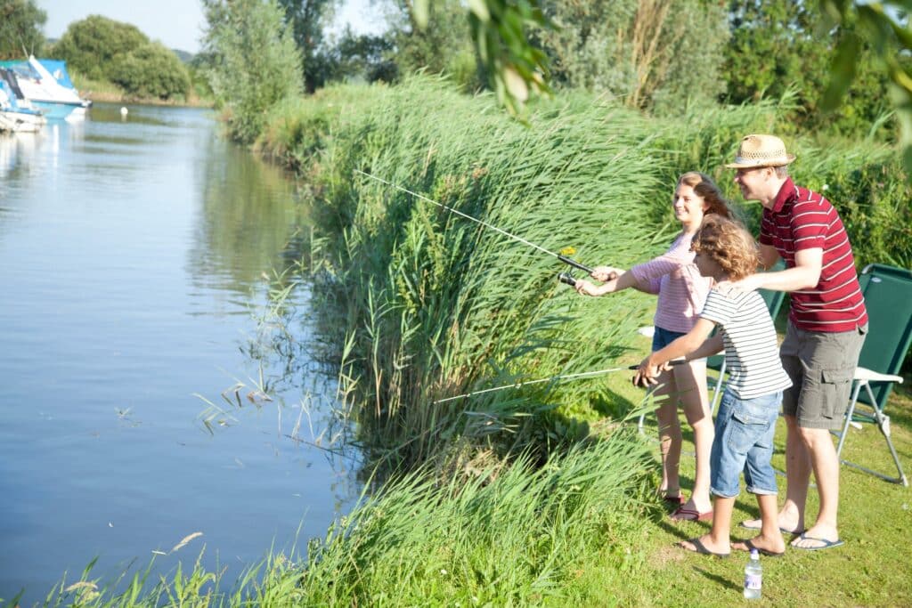 Family fishing together by the water during a holiday.