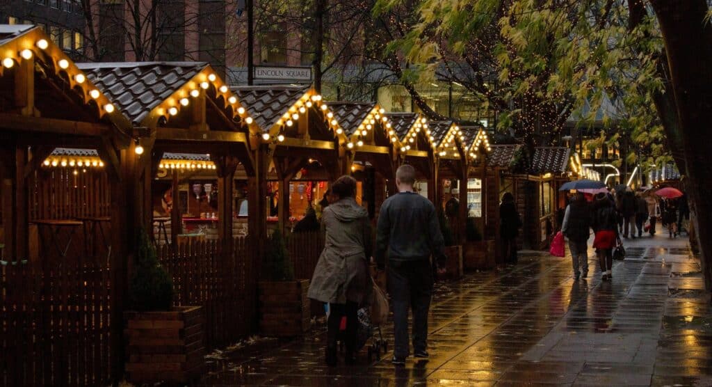 Festive Christmas market with twinkling lights on a rainy evening.