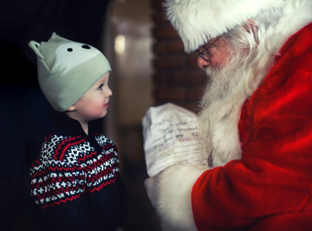 Festive Santa Claus reading a child's wishlist with a warm smile.