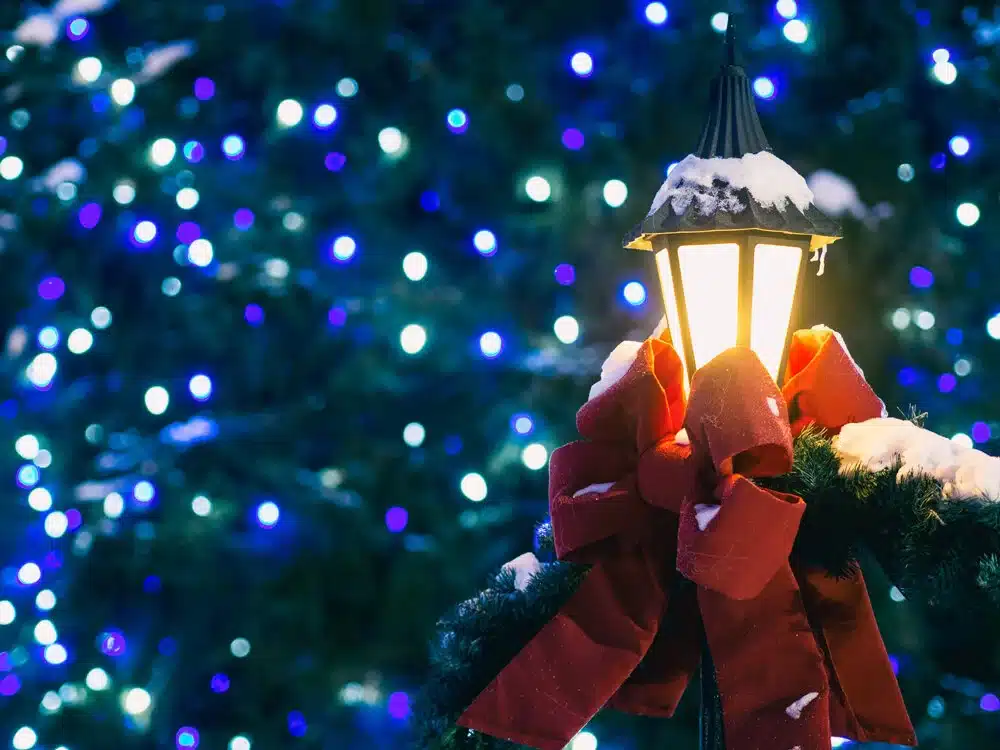 Festive lantern light with red ribbon bow infront of soft focus blue and white lights