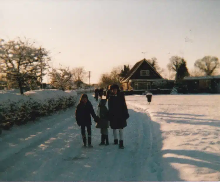 Family holding hands in the snow, pictured facing towards the camera