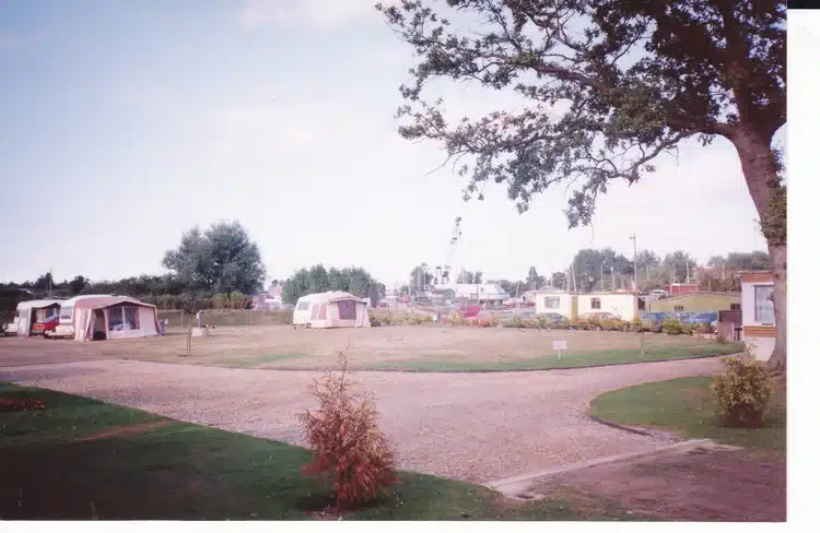 Tent pitches, pictured with greenery and a clear day