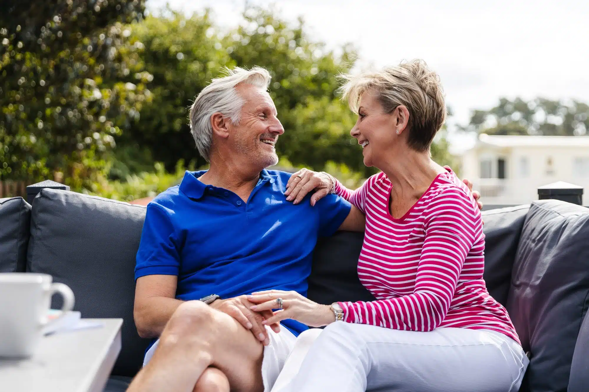 Happy couple sitting on an outdoor sofa, smiling at a holiday park
