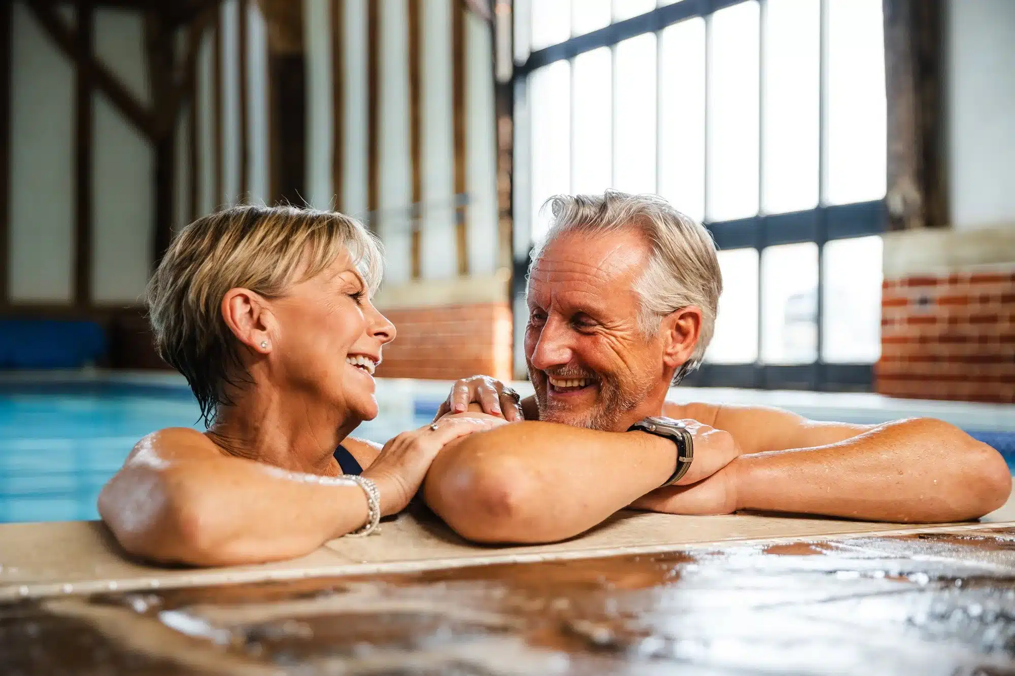 Happy couple enjoying an indoor swimming pool at Caldecott Hall Country Park.